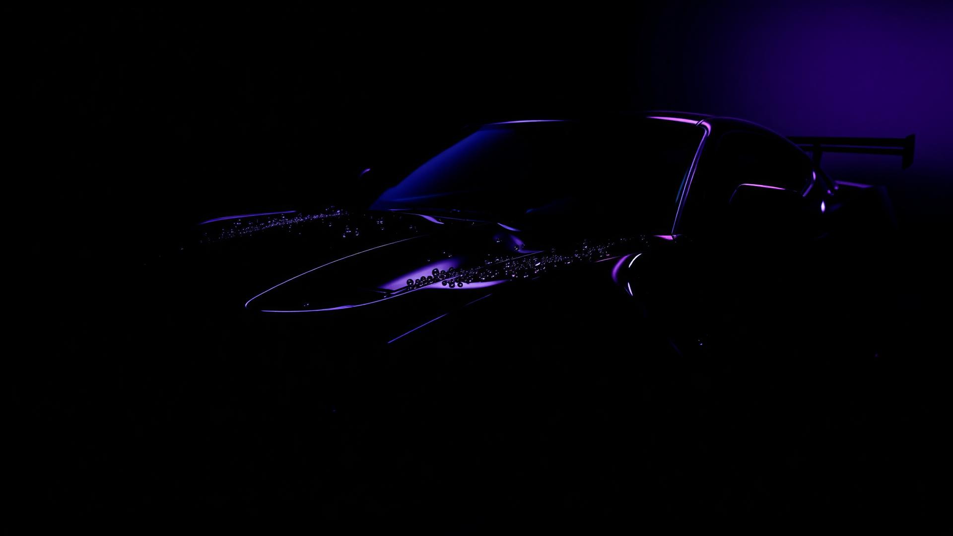 Glossy black sports car detailed under purple light